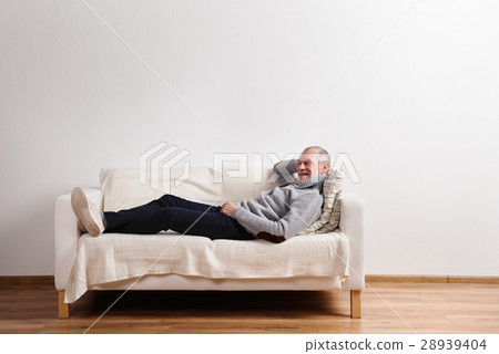 Senior man in gray sweater lying on sofa, studio 28939404