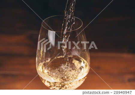 Pouring white wine from a bottle in a close  28940947