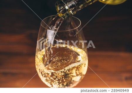 Pouring white wine from a bottle in a close up  28940949