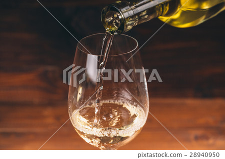 Pouring white wine from a bottle in a close up Pouring white wine from a bottle in a close up 28940950