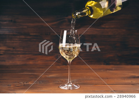 Pouring white wine from a bottle in a close up 28940966