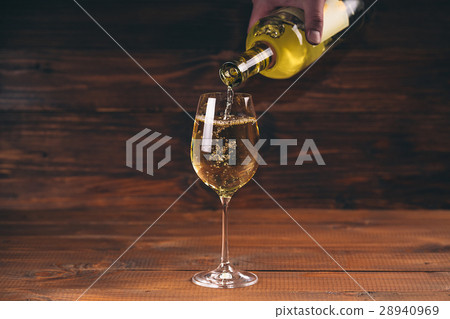 Pouring white wine from a bottle in a wineglasses Pouring white wine from a bottle in a wineglasses 28940969