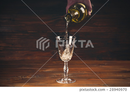 Pouring white wine from a bottle in a wineglasses Pouring white wine from a bottle in a wineglasses 28940970