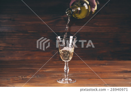 Pouring white wine from a bottle in a wineglasses Pouring white wine from a bottle in a wineglasses 28940971
