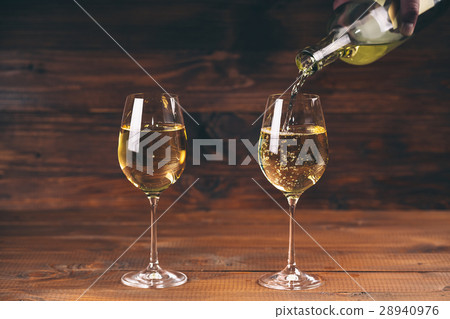 Pouring white wine from a bottle in a close up  28940976