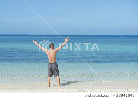 A man raising his hands at the beach 28941048