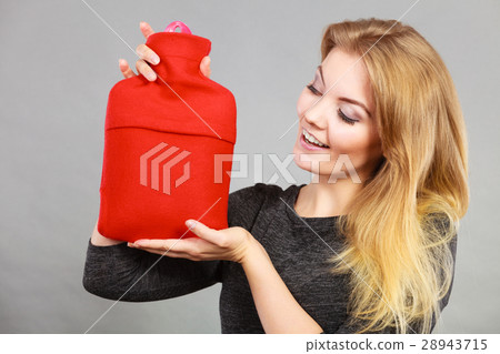 Woman holding warm red hot water bottle 28943715