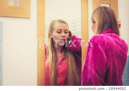 Woman looking at her reflection in mirror Woman looking at her reflection in mirror 28944082