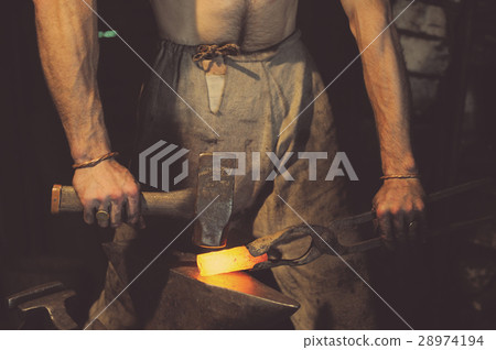 Blacksmith working metal with hammer on the anvil Blacksmith working metal with hammer on the anvil 28974194
