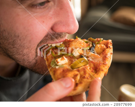 Man eating a slice of pizza 28977699