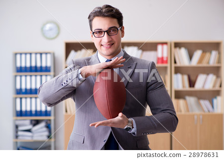 Businessman with american football in office Businessman with american football in office 28978631