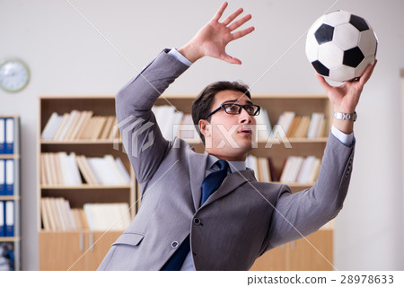 Businessman with football ball in office Businessman with football ball in office 28978633