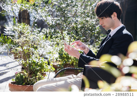 A man watching a smartphone on a bench A man watching a smartphone on a bench 28988511