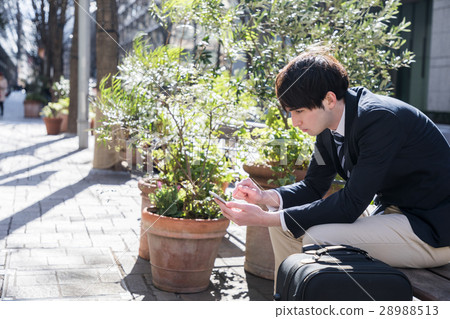 A man watching a smartphone on a bench 28988513