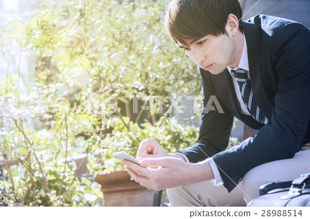 A man watching a smartphone on a bench 28988514