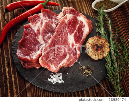 Raw pork neck steak on a stone plate. 28989474