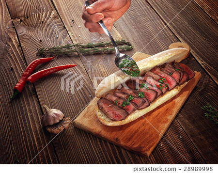 Sandwich with beef steak on a wooden stand. 28989998