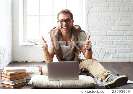 Young man smiling in front of the laptop 28995999