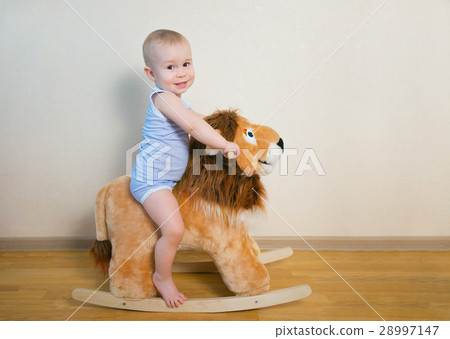 Cute small baby boy riding on the lion toy . Happy Cute small baby boy riding on the lion toy . Happy 28997147