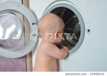 Little baby boy loading clothes into washing 28998443