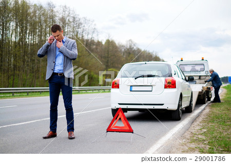 Man calling while tow truck picking up his broken 29001786