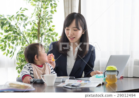 Working mother letting baby eat baby food 29012494