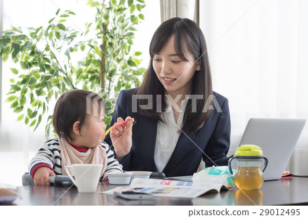 Working mother letting baby eat baby food Working mother letting baby eat baby food 29012495