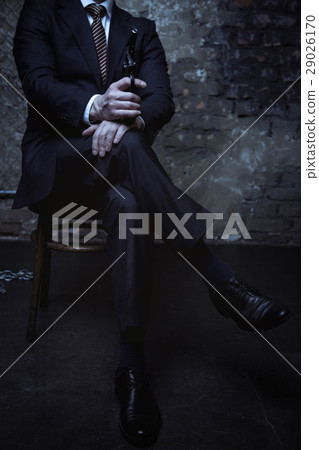 Attractive villain sitting with his legs crossed 29026170