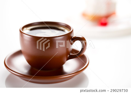 A brown cup of coffee with a cake in the A brown cup of coffee with a cake in the 29029730