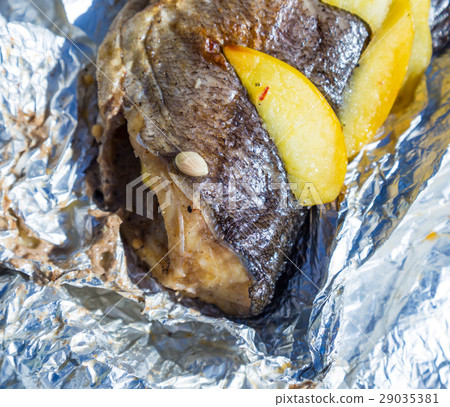 Baked fish in foil with lemon and apples outdoors Baked fish in foil with lemon and apples outdoors 29035381
