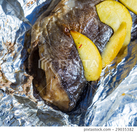 Baked fish in foil with lemon and apples outdoors Baked fish in foil with lemon and apples outdoors 29035382