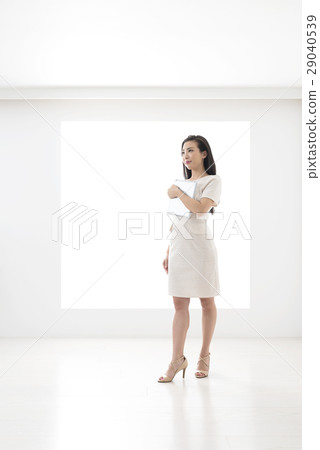 A young woman holding a tablet in front of a panel 29040539