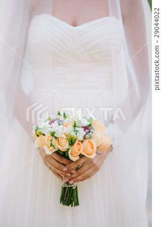 Beautiful woman in a white wedding dress holding a 29044022