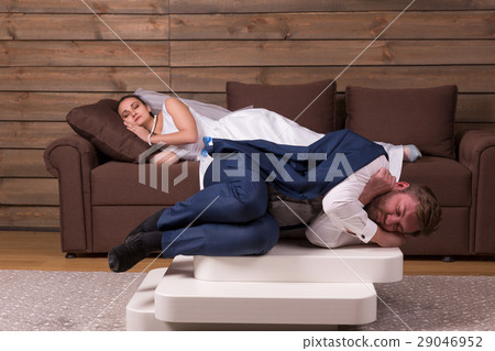 Tired bride and groom are sleeping on couch 29046952