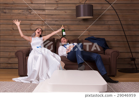 Drunk bride with bottle, groom sleeping on couch Drunk bride with bottle, groom sleeping on couch 29046959