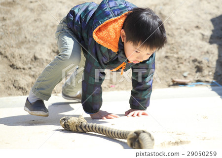 A boy holding on a rope and going up a slope 29050259