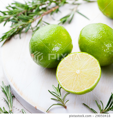 Fresh limes and rosemary on a wooden cutting board 29050418