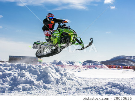 snowmobile rider jumping through snow. 29050636