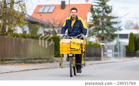 Postman riding his cargo bike carrying out mail Postman riding his cargo bike carrying out mail 29055769