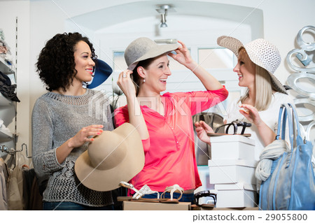 Girlfriends on shopping spree trying ladies hats  29055800