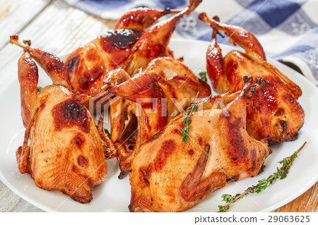 roasted quails with thyme on dish on white table roasted quails with thyme on dish on white table 29063625