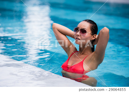 Woman wearing red swimsuit and sunglasses sitting 29064855