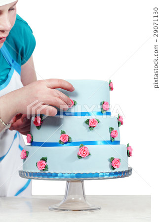 Woman decorates three-story blue cake 29071130