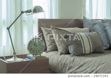 Reading lamp and clock next to modern bedding 29071341