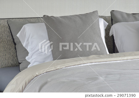 Gray pillow on white setting on bed with blanket 29071390