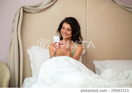 Woman with phone in bed. Woman with phone in bed. 29083323