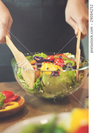 Woman cooking salad with vegetables. Woman cooking salad with vegetables. 29084252