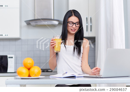 Girl in glasses writing home task at kitchen. 29084637