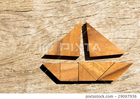 Tangram puzzle in sailing boat on wood background 29087936