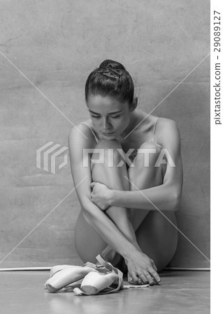Tired ballet dancer sitting on the wooden floor on 29089127